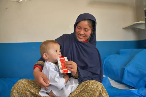 On 2 May 2023, 18-month-old Mahdi eats a sachet of ready-to-use therapeutic food (RUTF) in his mother Anar's lap at Daikundi Provincial Hospital in Afghanistan.