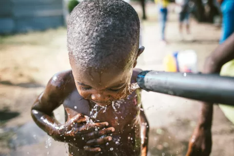 Boy showering in a water pump installed by a UNICEF Angola WASH project