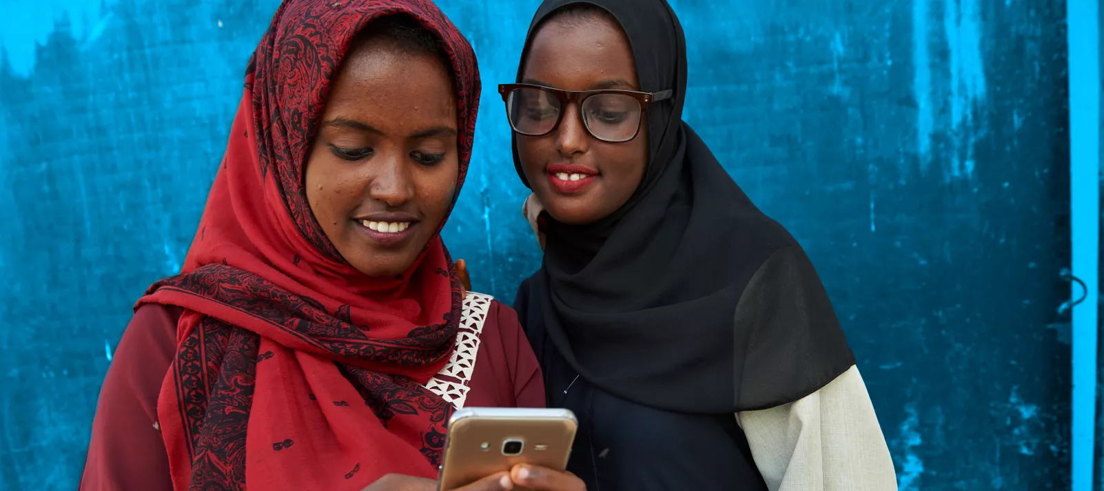 two adolescent girls looking at a mobile phone screen