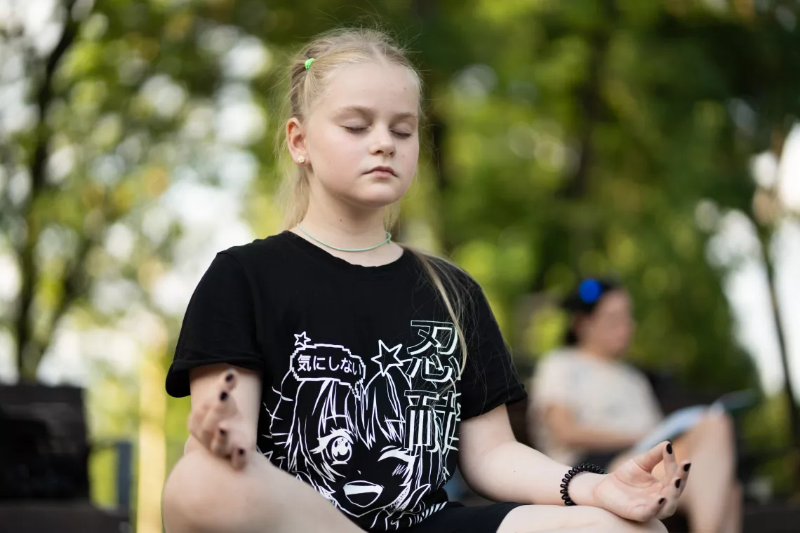A girl sits in a cross-legged seat during a yoga class.