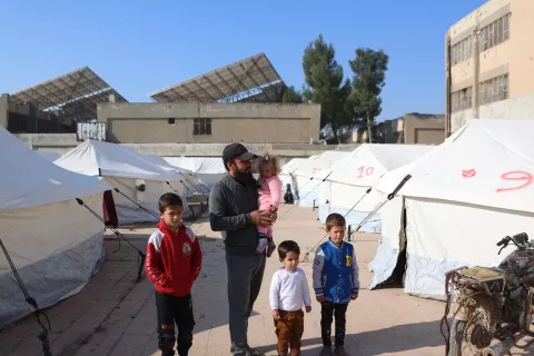 A father and four children stand outside makeshift tents