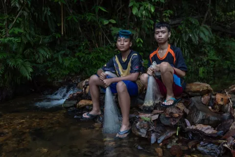 Two Iban teenagers sitting by river bank