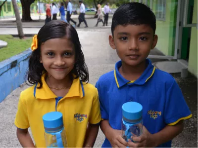 Two children hold their reusable plastic bottles at a launch event in Fuvahmulah.