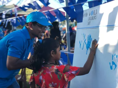 A UNICEF staff member interacts with a child at World Children's Day in 2018.