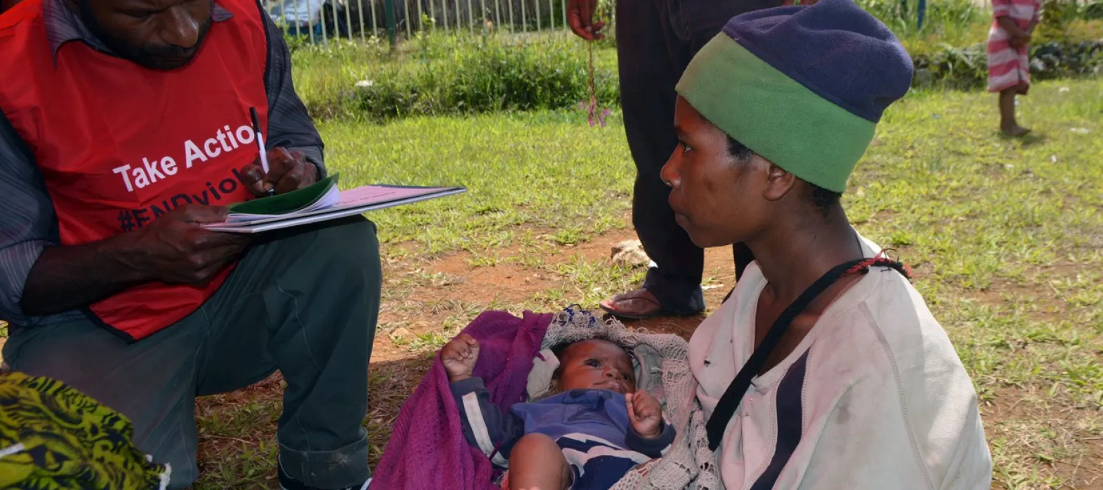 Angela and her son get attended to by a health worker at a child health outreach site.