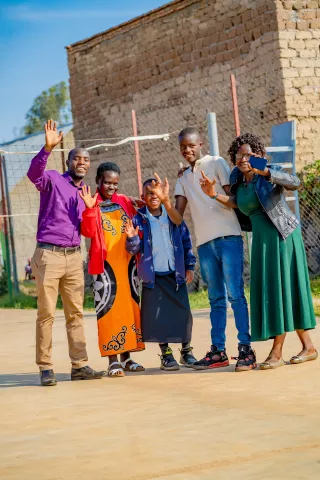 Murava, his mother Martine, his teacher Emmanuel, his friend Aline, and her mother Dorcas, pose for a picture together.