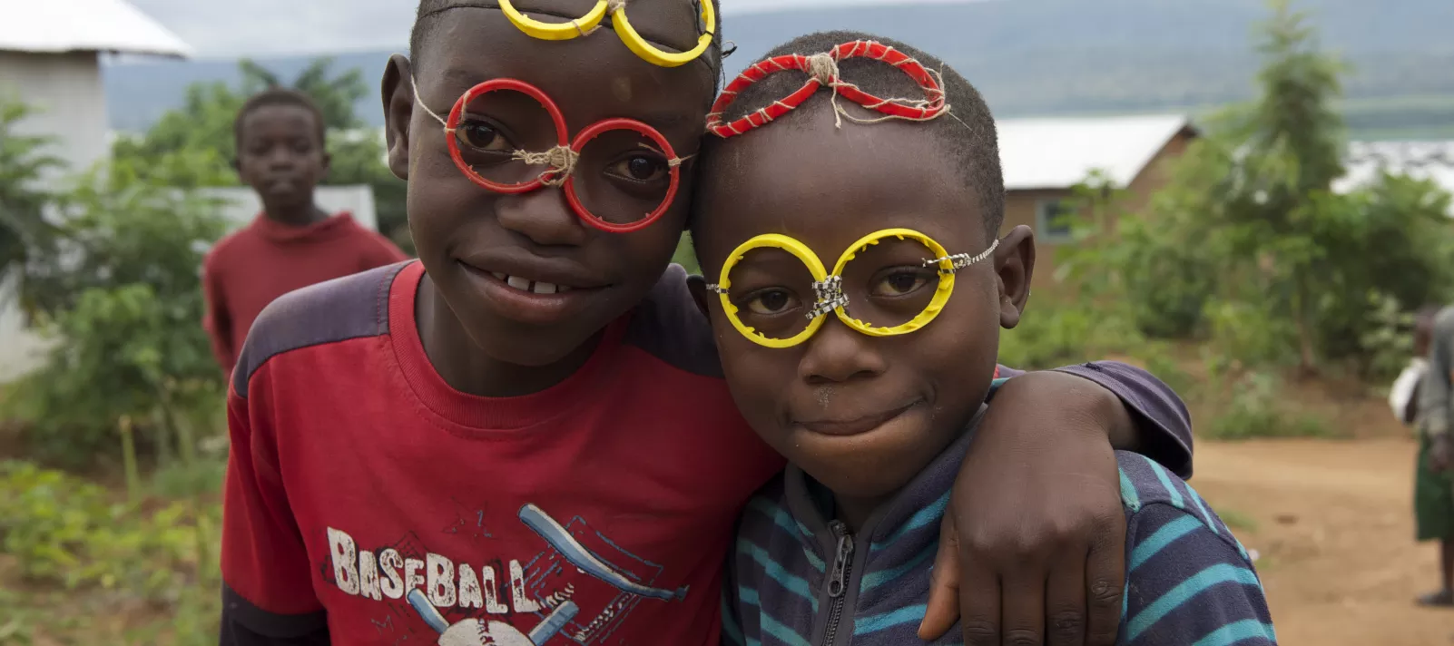 Two young boys smile at the camera wearing homemade glasses