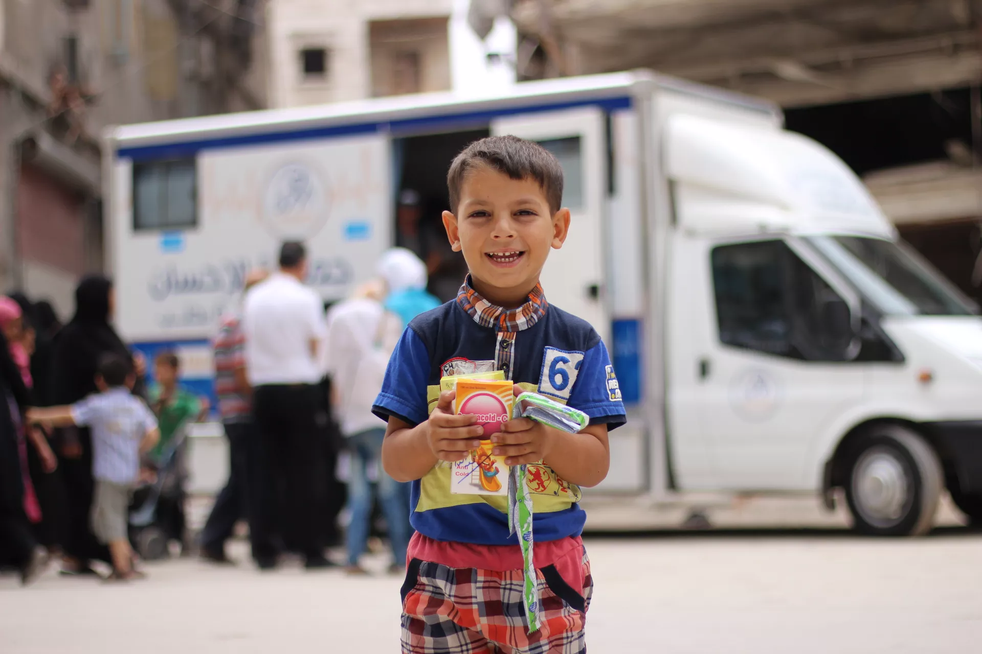 A boy stands in front of a mobile health clinic, Syrian Arab Republic