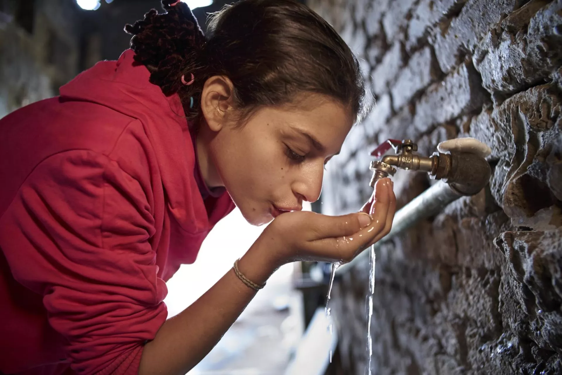 一个女孩正在水龙头接水喝