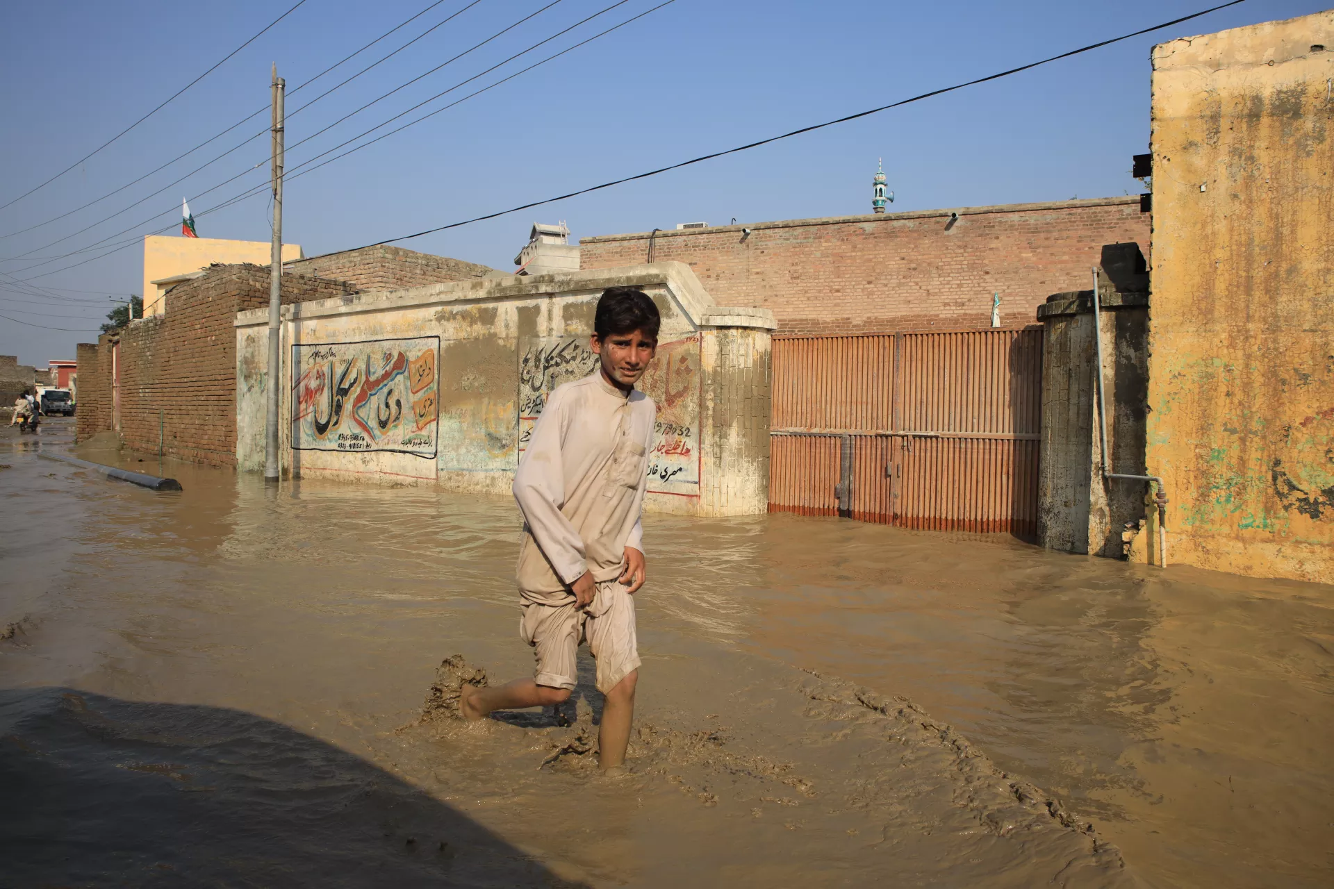 Boy wading through a flooded street in Pakistan