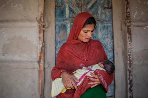Pakistan. A woman looks down at her newborn baby.