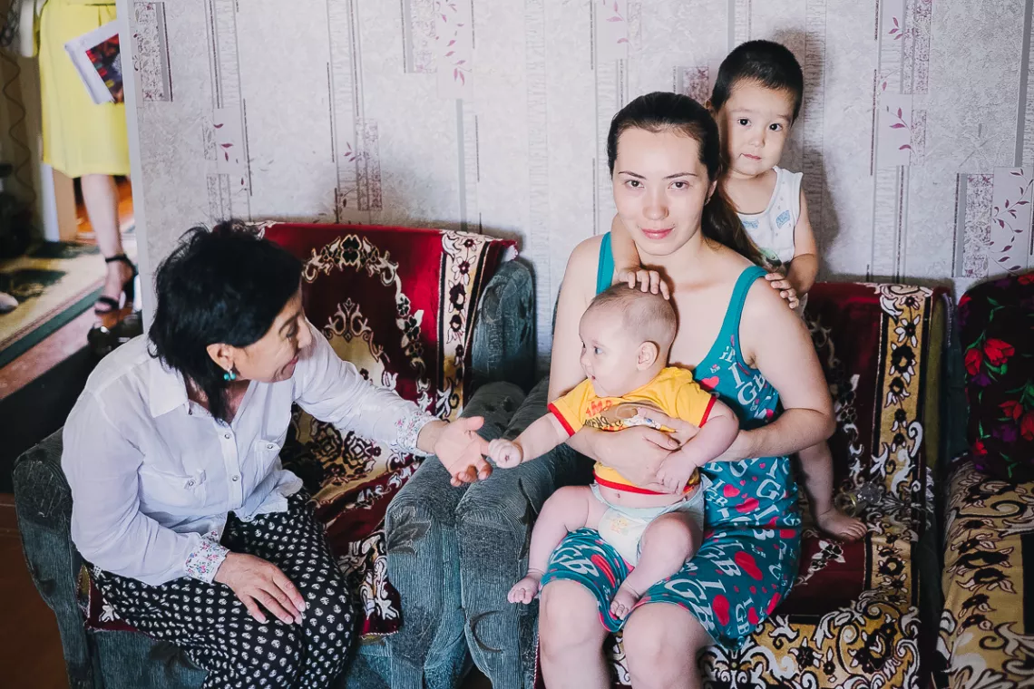 Two women sit with children on a couch, Kazakhstan