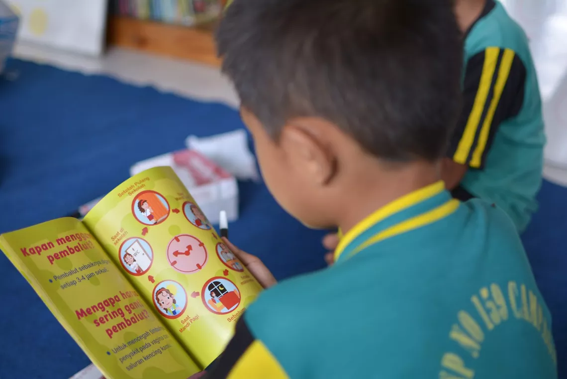 Un garçon lit un livre sur la menstruation, Indonésie