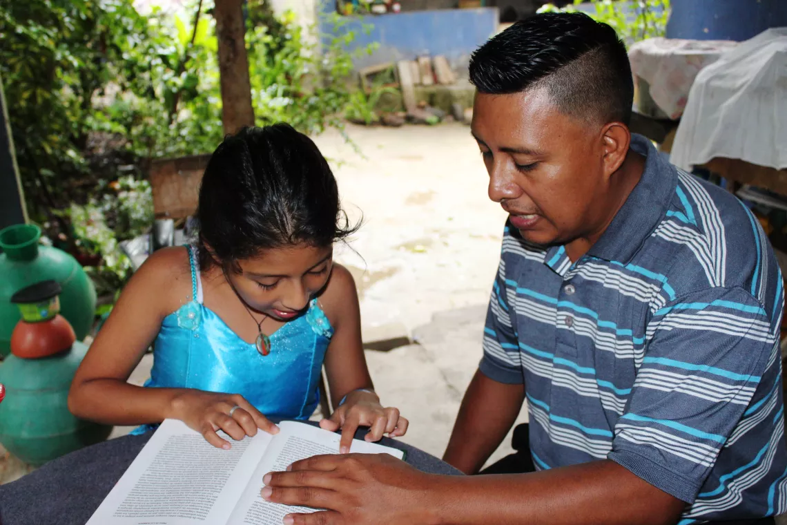 A father helps his daughter with homework, El Salvador