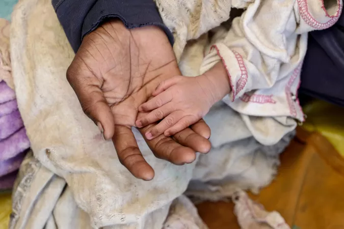 An adult's palm holds a child's hand