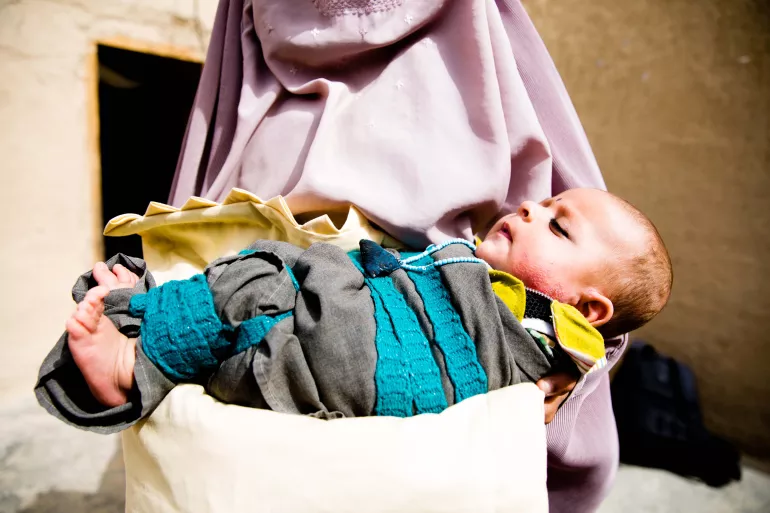 A woman holds a sleeping baby, Afghanistan