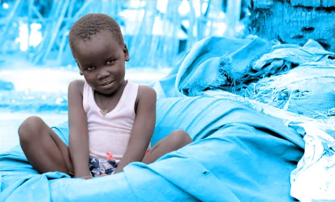 A little boy sitting close to water kiosk in Juba, South Sudan