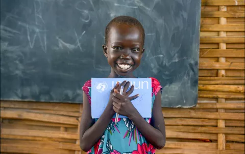 A little girl is holding her book and smiling 