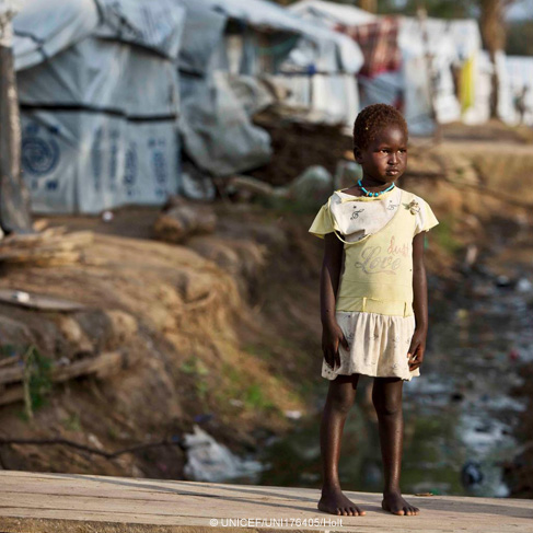Una niña está parada en un puente sobre un canal de drenaje en Sudán del Sur