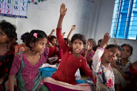 Eight-year-old Rohingya refugee Yasmin Akther (centre) and other students raise their hands to answer a question during a class at the Prajapatti UNICEF Learning Center in Cox's Bazar, Bangladesh, June 2017.