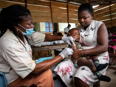 A mother holds her son as he receives yellow fever vaccine