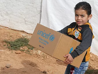 In the town of Ersal, East Lebanon, near the Syrian border, a girl walks with a box containing winter clothing provided by UNICEF in December 2018.