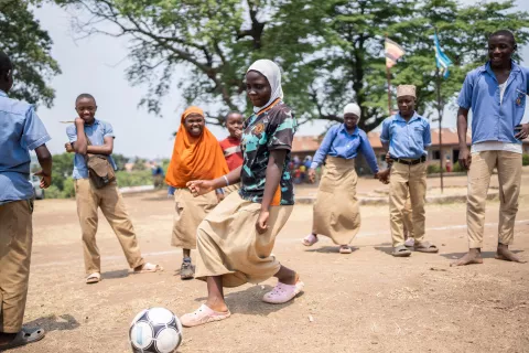 Girl with group of friends playing football in Uganda 