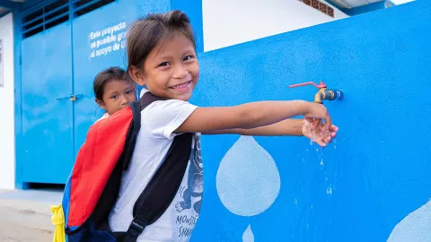 Girl smiles while washing her hands at a tap next to the Solar Water Treatment Plant installed in the community of San Francisco de Guayo, Venezuela, 2023.