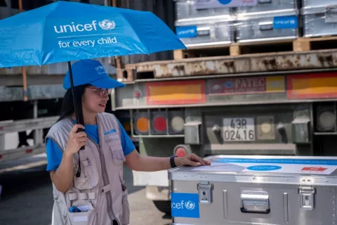 UNICEF staff HO Tran Thanh Huyen poses for photos with the early childhood development kits for emergency relief after unloading from from the trucks in a warehouse yard in Da Nang, Vietnam.