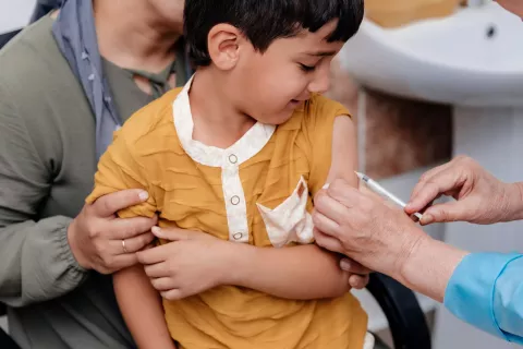 A child is getting his vaccine shot through the needle 