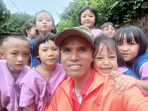 Adult Tawin Srikaew with schoolchildren.