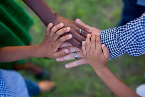 The image of children's and adults' hands joining together conveys cooperation and care.