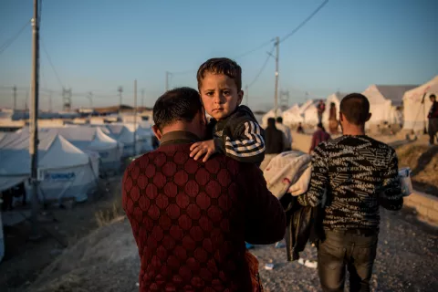 Niño en brazos de padre en un campo de refugiados