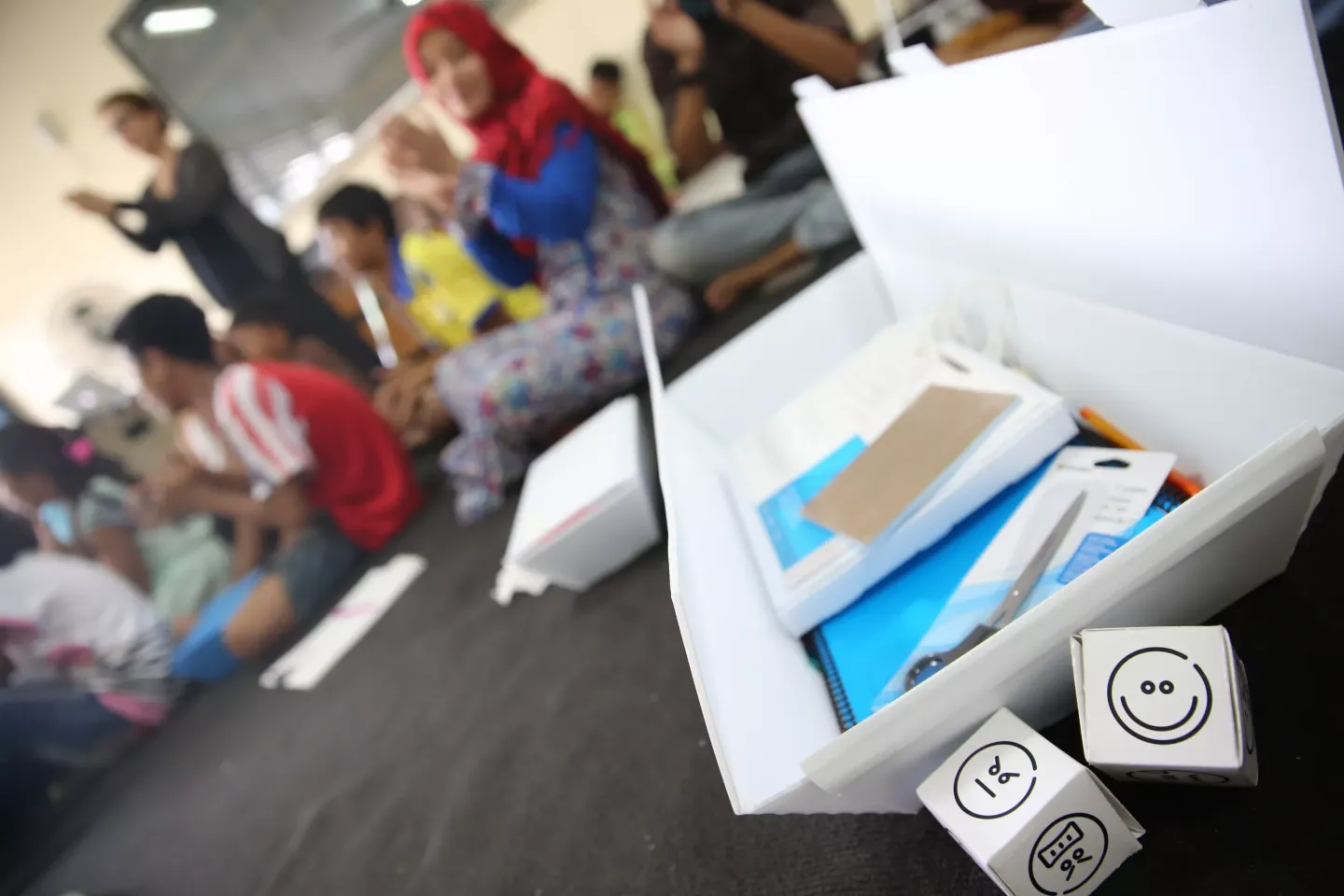 A UNICEF Supply Kit sits open in a classroom in Indonesia where adolescents are participating in activities.