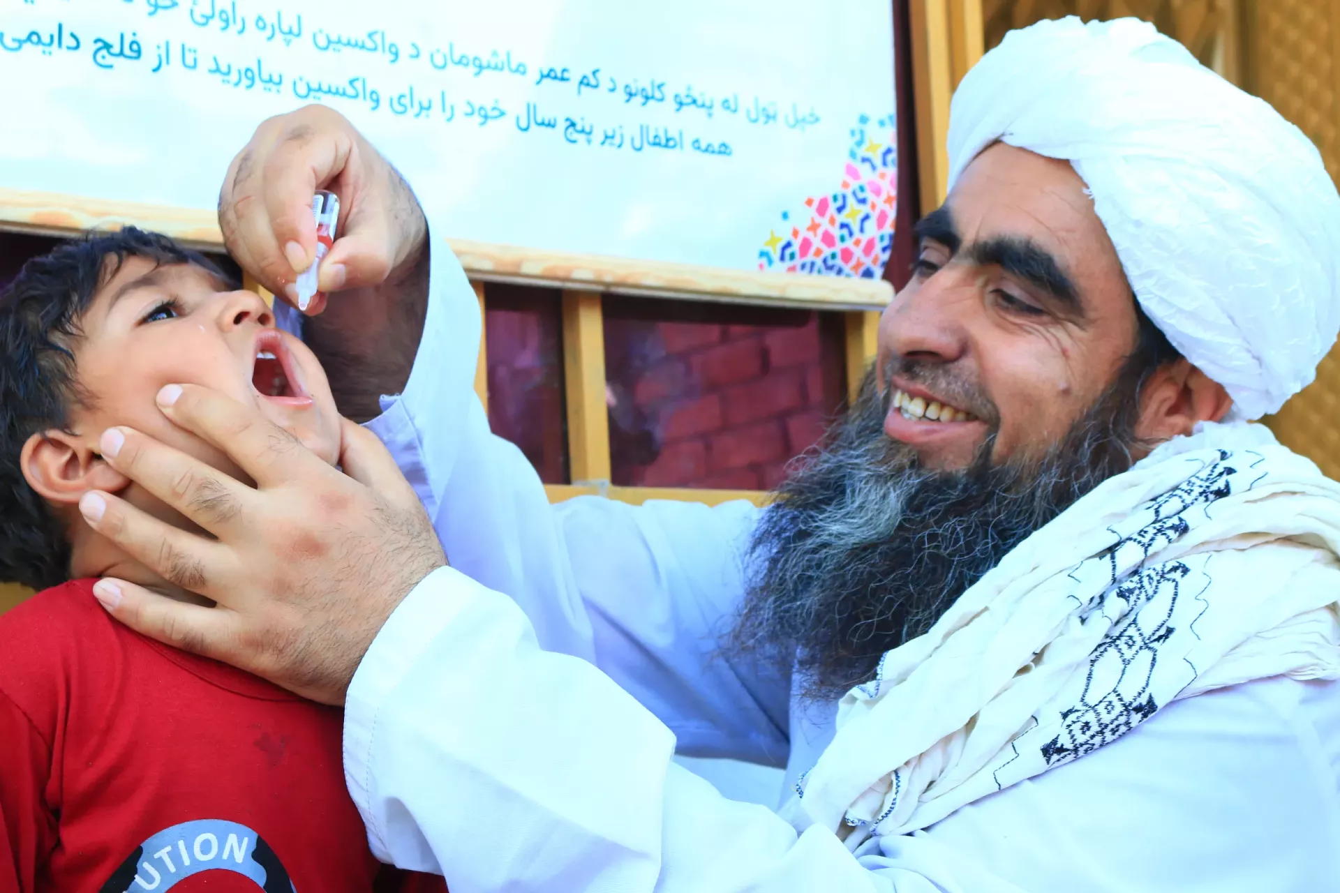 Rabani, a religious leader vaccinate a child during the May, 2025 NID campaign in Surkhrud district of Nangarhar. 