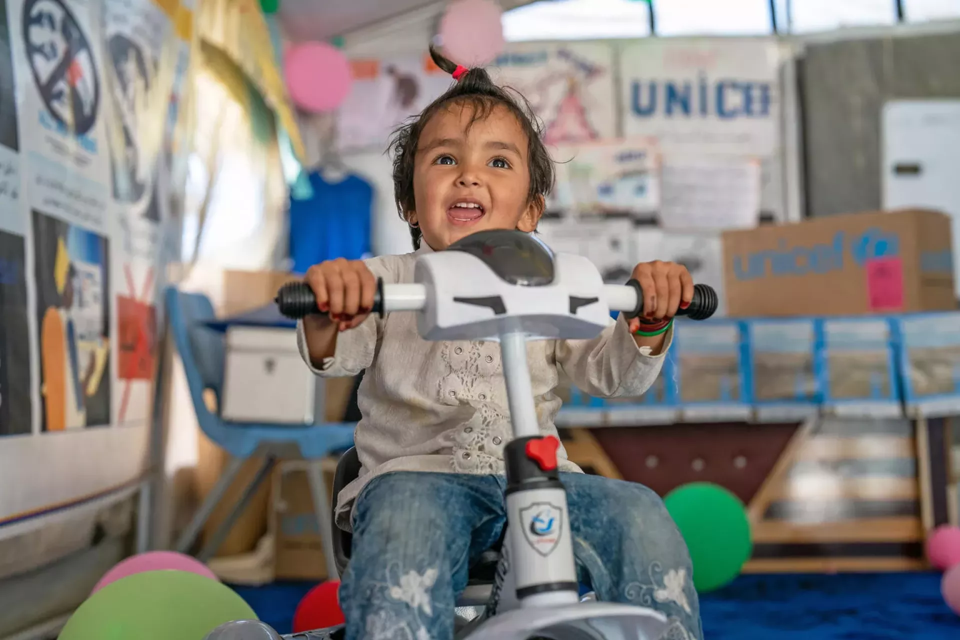On 7 May 2024, 3-year-old Kubra plays on a bicycle&nbsp;at the UNICEF-supported child-friendly space on the Torkham border crossing with Pakistan in Nangarhar Province, eastern Afghanistan.