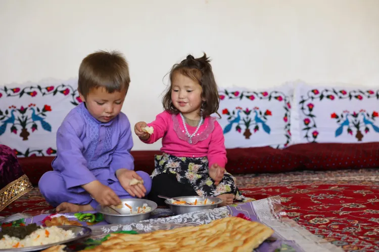 Azar (2) and her brother Bin Yamin (3) eats rice and vegetables prepared by their mother, with micronutrient powder (MNP) added to the meal. 