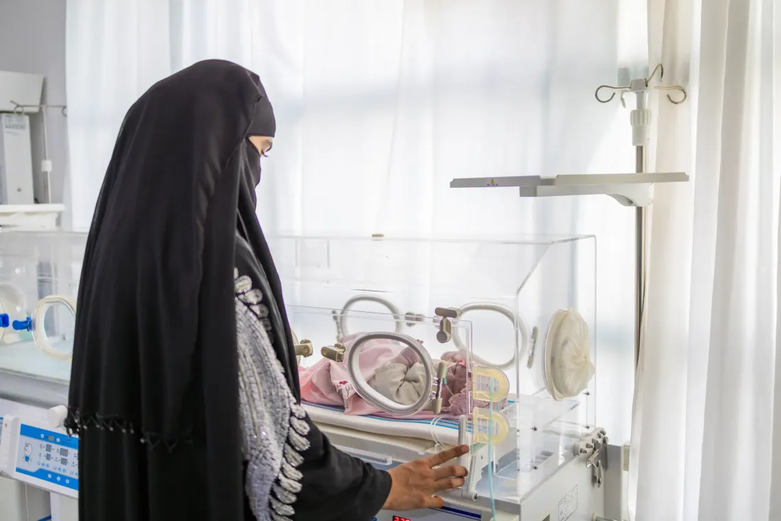 Mah Jan stands beside the newborn radiant warmer while observing the newborn during routine postnatal care in Herat Afghanistan.