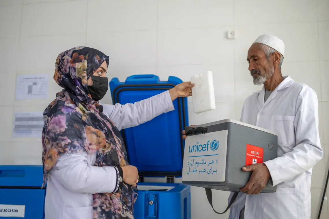 Sonia Ghafoori, a fixed vaccinator at the Kahdistan Health Clinic, prepares and hands over vaccines to Abdul Aziz for his outreach visit, in Kahdistan Afghanistan. 