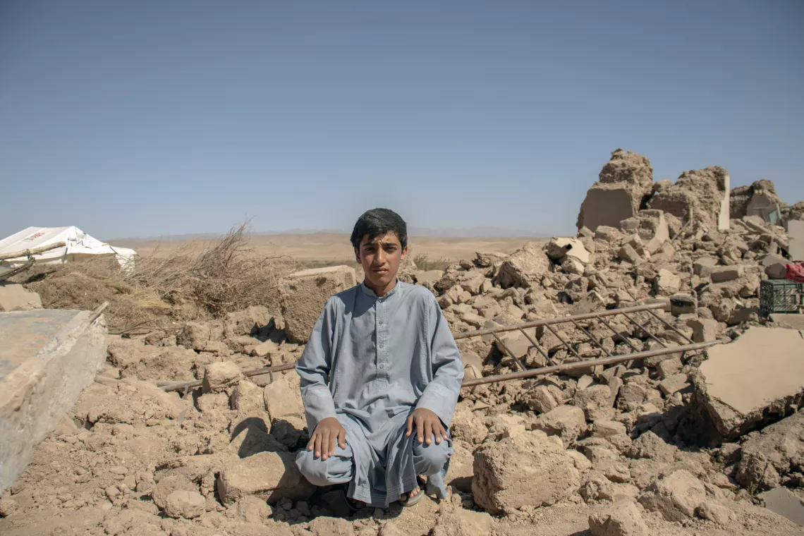 On 9 October 2023, Lobair Ahmad, 14 years old, sits among rubble from the earthquake two days prior, which shook his community in Zinda Jan district, Herat province, Afghanistan.