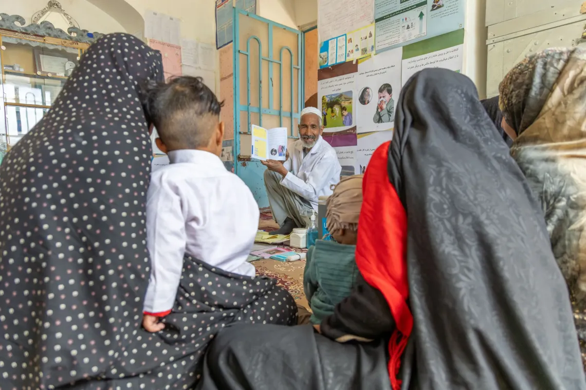 Mothers and children from the community gather at the outreach site, listening to importance of vaccination as Abdul shares information with them in Kahdistan, Afghanistan. 