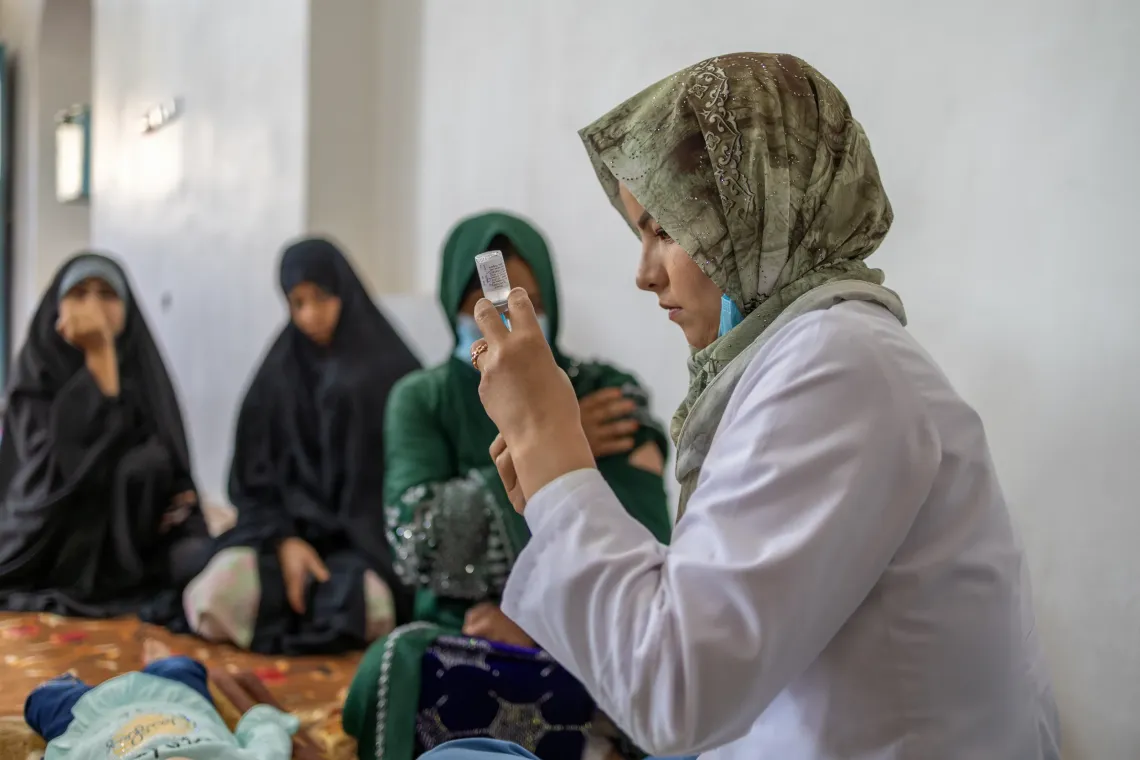 Zahra prepares Tetanus Diphtheria vaccine injection to administer it to a pregnant mother sitting nearby in Balkh, Afghanistan. 