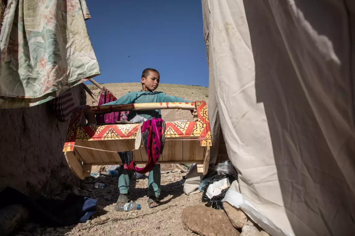 On 14 May 2024, Deen Mohammad, 8, carries his baby sister's cradle where his home used to be in Shaikh Jalal Village, Baghlan-e-Jadid District, Baghlan Province, Afghanistan.