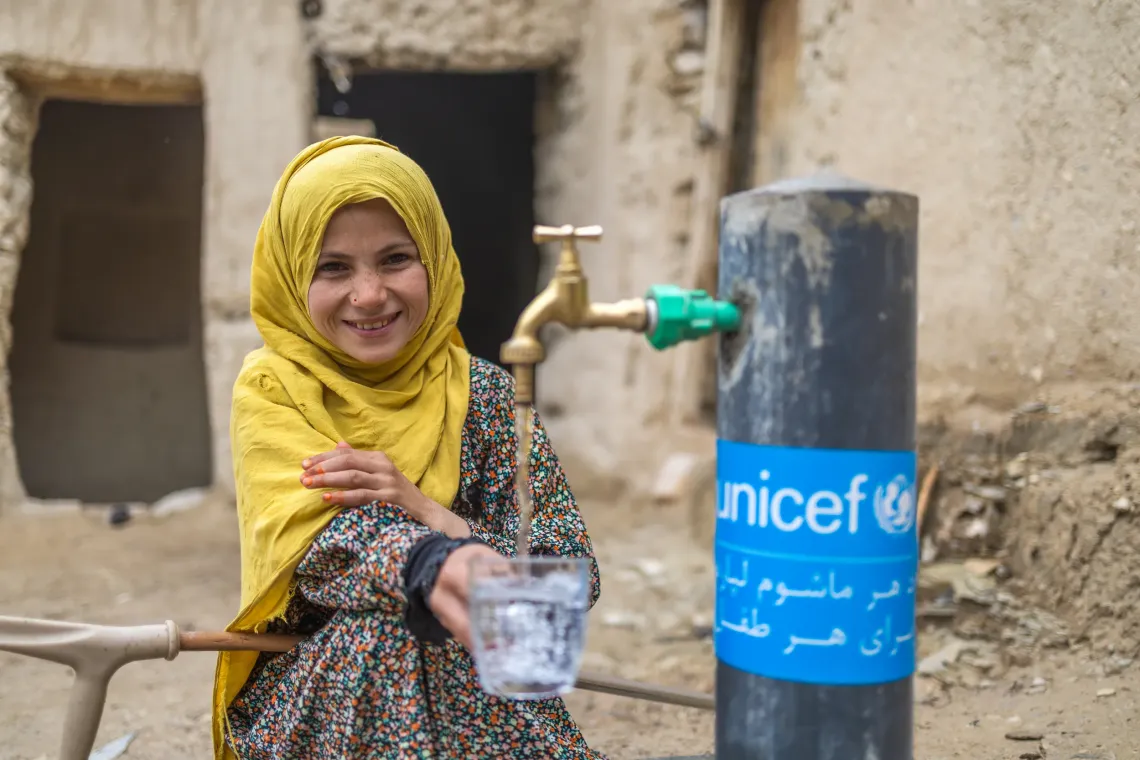 Humira, 12, fills a glass with drinking water from a tap near her home in Tagab Ghalmin village, Ghor Province. 
