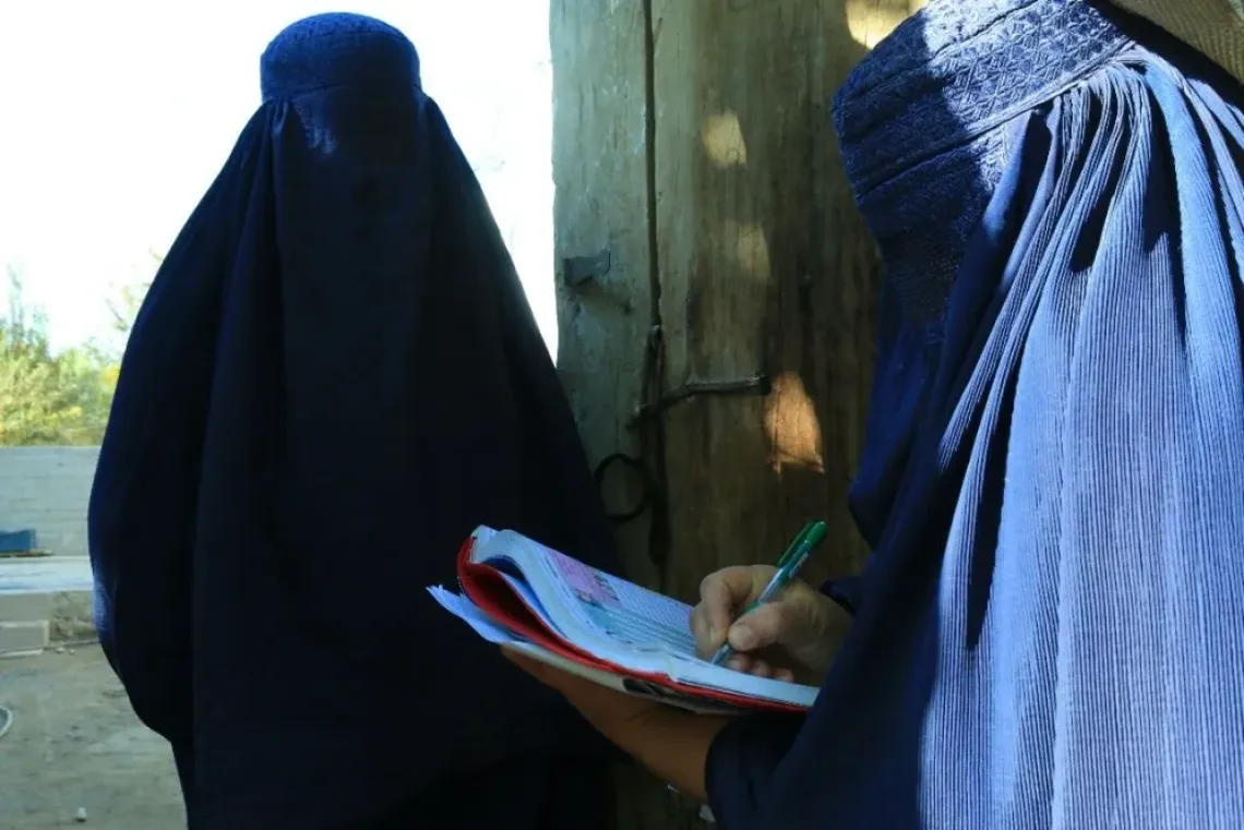 Sediqa (45), a social mobilizer for polio programme talks to female member of a household in Laghman and writes the details in her registration book, making sure every child is counted and followed up during the polio vaccination campaign. 