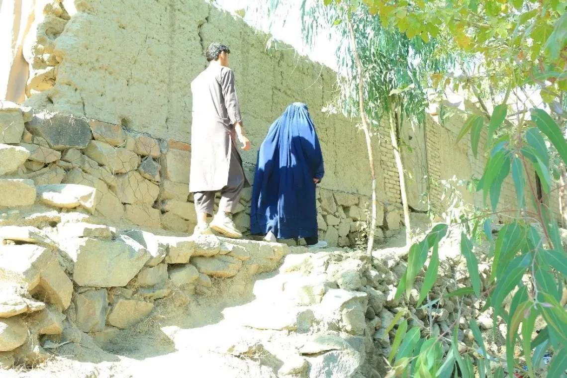 Sediqa (45) walks along with her son, who serves as her mahram, as they move from one household to the next during the polio campaign in Laghman Province. 