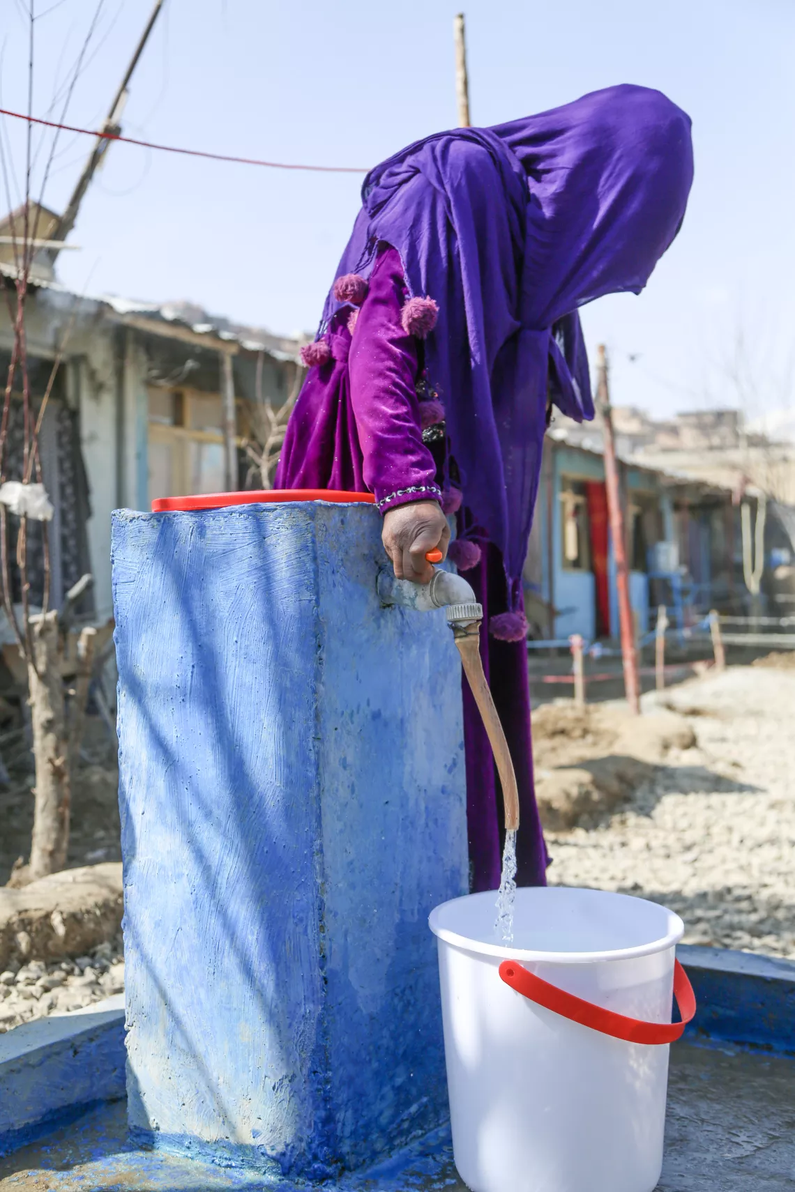 Kamina collects water from a tap positioned just outside her home in Qala-e Abdul Ali informal settlement for internally displaced persons in Kabul, Afghanistan. 
