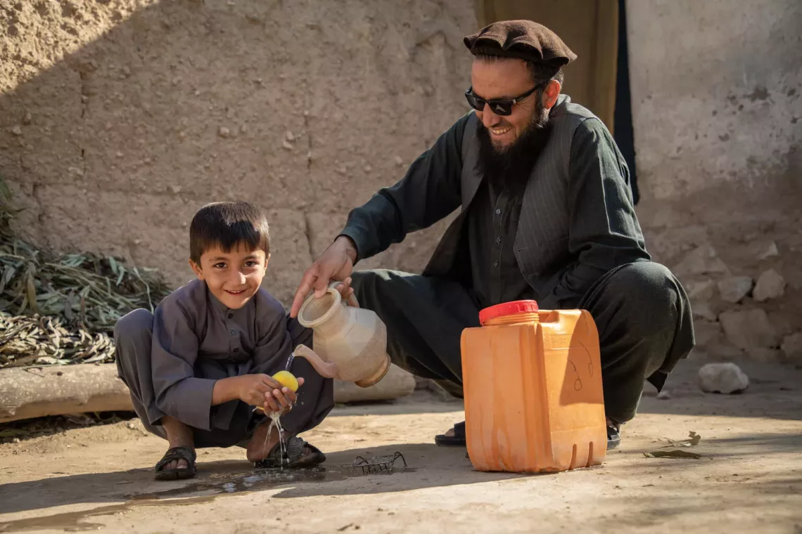 On 17 November 2024, Qari Rahmatullah, head of community council or 'shura' in charge of CLTS, helps his 6-year-old son, Muhammad Haroon, wash his hands at their house in Sheikh Mesri village, Sorkhrod district, Nangarhar province, Afghanistan.