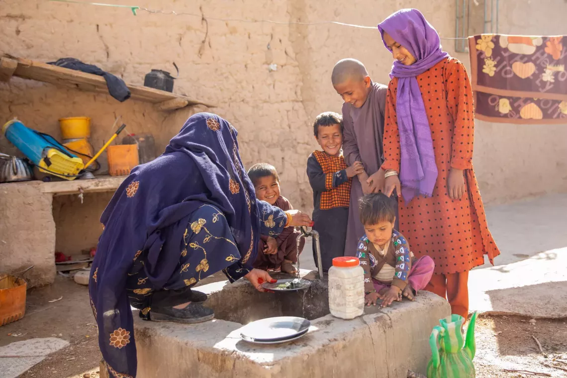 On 10 February 2025, Amina, surrounded by her children, is washing dishes by the new tap at home, thanks to a piped water system recently inaugurated in her village in Farah Province, western Afghanistan.