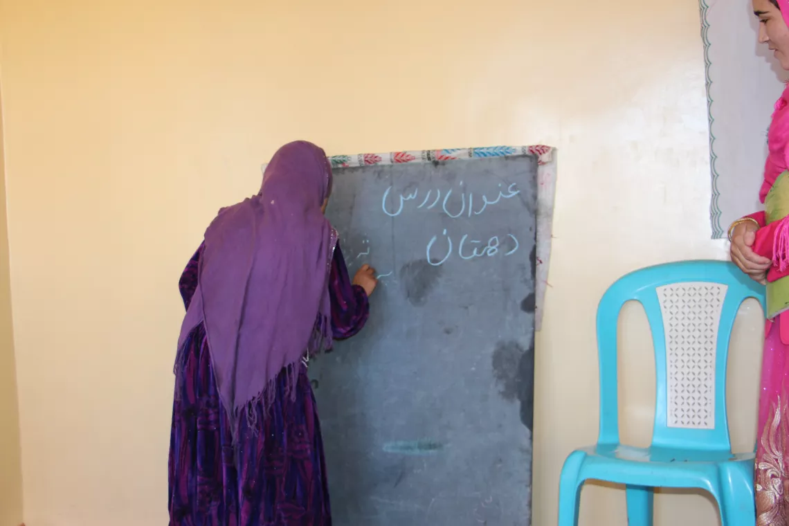 A girl with purple scarf practicing her writing skills